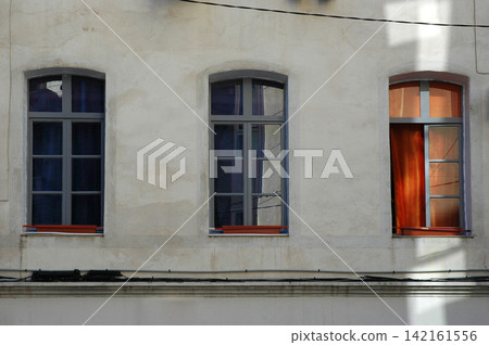 Three vintage windows on a concrete building facade 142161556