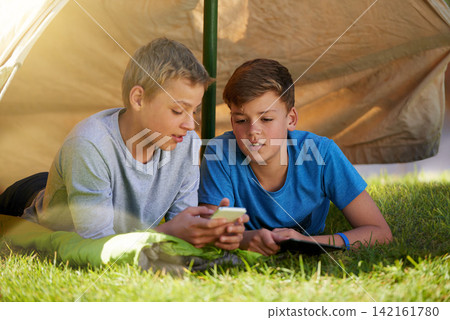 Children, phone and tent on grass for camping, virtual games and outdoor recreation on holiday. Young boys or kids and talking with mobile and curious for online fun and adventure on summer vacation Children, phone and tent on grass for camping, virtual games and outdoor recreation on holiday. Young boys or kids and talking with mobile and curious for online fun and adventure on summer vacation 142161780