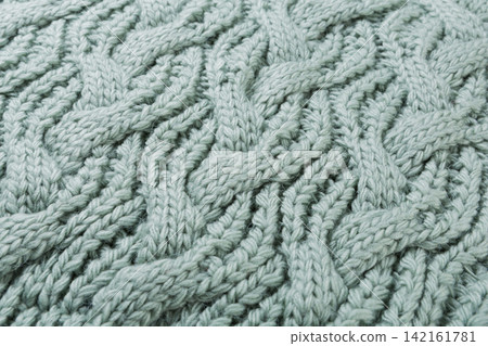 Sage green knitted wool fabric texture close up. Cable knit pattern background for winter fashion design Sage green knitted wool fabric texture close up. Cable knit pattern background for winter fashion design 142161781
