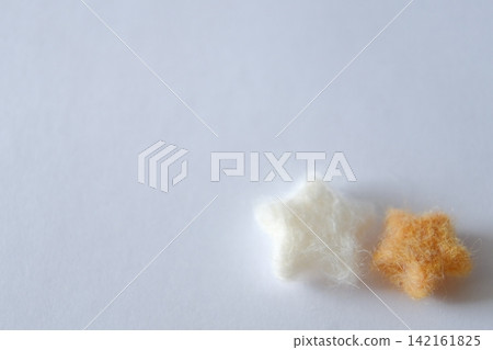 A pair of stars made from white and orange wool felt, copy space A pair of stars made from white and orange wool felt, copy space 142161825