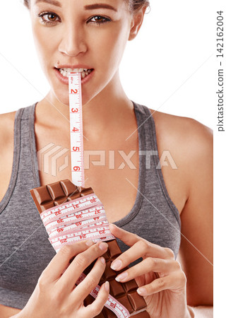 Woman, chocolate and bite with measuring tape for unhealthy diet with junk food in studio. Female person, eating and sugar craving or weight gain with snack or sweet temptation on white background Woman, chocolate and bite with measuring tape for unhealthy diet with junk food in studio. Female person, eating and sugar craving or weight gain with snack or sweet temptation on white background 142162004