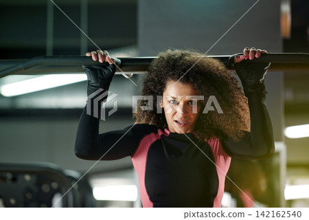 Portrait, woman and pull up exercise at gym on bar for muscle, wellness or healthy body. Chin up, fitness and strong person with equipment at club for power, training and workout with face in Brazil Portrait, woman and pull up exercise at gym on bar for muscle, wellness or healthy body. Chin up, fitness and strong person with equipment at club for power, training and workout with face in Brazil 142162540