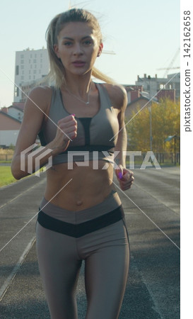Vertical video. Pretty sporty woman running in the sports stadium. Fitness, workout and technology. Vertical video. Pretty sporty woman running in the sports stadium. Fitness, workout and technology. 142162658