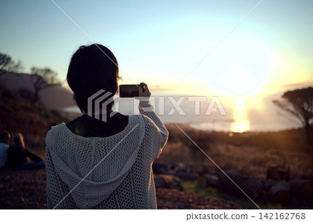Hiking, photography and woman with phone at sunset sky, nature and mountain to relax on holiday adventure. Smartphone, trekking and person with view of island, ocean and memory on vacation from back Hiking, photography and woman with phone at sunset sky, nature and mountain to relax on holiday adventure. Smartphone, trekking and person with view of island, ocean and memory on vacation from back 142162768