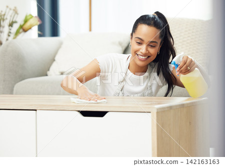 Woman, spray and cloth on table with smile, thinking or domestic housework in living room. Girl, person or cleaner with bottle, chemical or liquid to shine wood in home for cleaning service in Mexico Woman, spray and cloth on table with smile, thinking or domestic housework in living room. Girl, person or cleaner with bottle, chemical or liquid to shine wood in home for cleaning service in Mexico 142163163