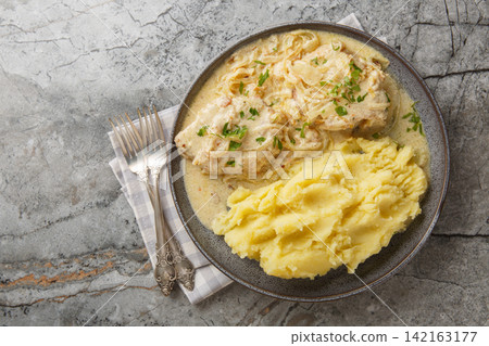 German Zwiebel schnitzel pork cutlets with a rich onion cream sauce with mashed potatoes closeup on the plate. Horizontal top view German Zwiebel schnitzel pork cutlets with a rich onion cream sauce with mashed potatoes closeup on the plate. Horizontal top view 142163177