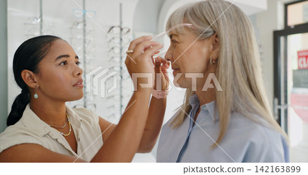 Woman, glasses and optician in store for choice, decision or customer service consultation. Eye care, doctor and mature client check lens on new frame for health, vision or help in optometry shop Woman, glasses and optician in store for choice, decision or customer service consultation. Eye care, doctor and mature client check lens on new frame for health, vision or help in optometry shop 142163899