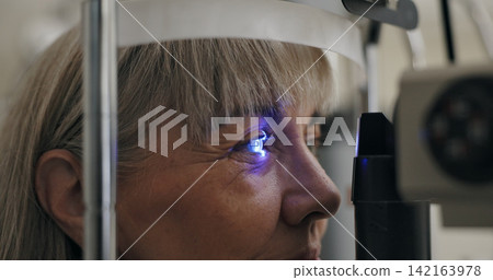Patient, slit lamp or ophthalmology as eye test, medicine or optometry as healthcare technology. Mature woman, eyeball or light in glaucoma, exam or consultation to diagnose lens, cornea or myopia Patient, slit lamp or ophthalmology as eye test, medicine or optometry as healthcare technology. Mature woman, eyeball or light in glaucoma, exam or consultation to diagnose lens, cornea or myopia 142163978