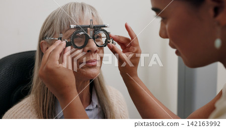 Women, optometrist and patient with trial lens for eye exam, vision test and prescription fro glasses at store. Doctor, consultation and equipment with assessment for eyesight, care and support Women, optometrist and patient with trial lens for eye exam, vision test and prescription fro glasses at store. Doctor, consultation and equipment with assessment for eyesight, care and support 142163992