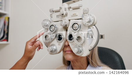Phoropter, test and optometrist for vision, eye and medical for optical exam or consultation. Optometry, technology and analysis machine, female patient at professional ophthalmologist clinic Phoropter, test and optometrist for vision, eye and medical for optical exam or consultation. Optometry, technology and analysis machine, female patient at professional ophthalmologist clinic 142164096