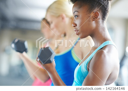Black woman, dumbbell and serious for workout in gym for fitness, class and muscle growth. Female person, weight and concentrated for exercise in center for training, sport and strength development Black woman, dumbbell and serious for workout in gym for fitness, class and muscle growth. Female person, weight and concentrated for exercise in center for training, sport and strength development 142164146