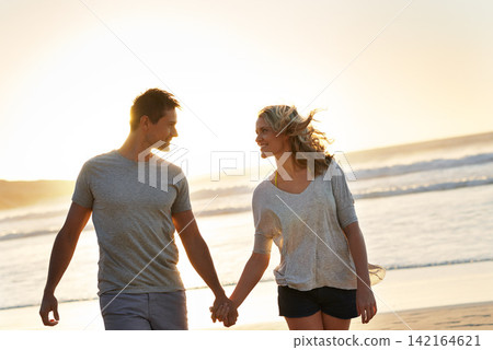 Holding hands, smile and couple with love at beach, ocean and sea for affection, bonding or to relax. People, partners and romance for care together on vacation, holiday and travel in Australia Holding hands, smile and couple with love at beach, ocean and sea for affection, bonding or to relax. People, partners and romance for care together on vacation, holiday and travel in Australia 142164621