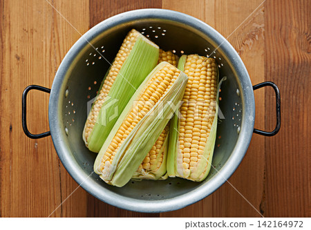 Closeup, corn or maize on table for fruit, wellness or healthy nutrition in home meal or kitchen. Cobs, background or above of natural produce for raw organic food, fiber or vitamin b in lunch diet Closeup, corn or maize on table for fruit, wellness or healthy nutrition in home meal or kitchen. Cobs, background or above of natural produce for raw organic food, fiber or vitamin b in lunch diet 142164972