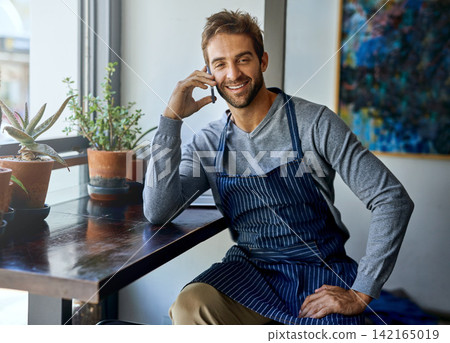 Small business, cafe and man with phone call, apron and relax in coffee shop for networking. Communication, working and restaurant manager, waiter or owner with smartphone, conversation and service 142165019