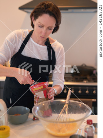 Woman, kitchen and baking in home, measure and ingredients for weekend activity. Food, pastry and cooking with recipe for hobby and fun, prepare and cake or baker in house for dessert or pudding 142165323
