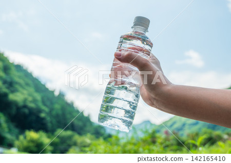 Blue sky and hand holding a plastic bottle Blue sky and hand holding a plastic bottle 142165410
