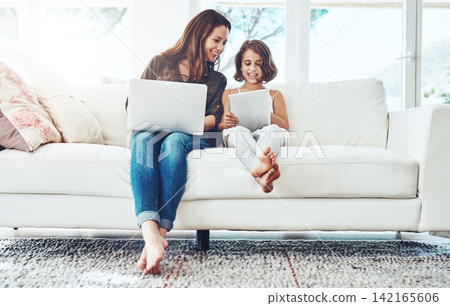 Laptop, tablet and mother with child on sofa for streaming movies, happiness and bonding together in living room. Family, mom and young girl with technology for watching videos, film or relax in home Laptop, tablet and mother with child on sofa for streaming movies, happiness and bonding together in living room. Family, mom and young girl with technology for watching videos, film or relax in home 142165606