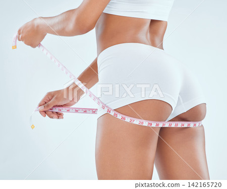 Woman, hands and butt with tape measure for weight loss, diet or nutrition on a gray studio background. Closeup of female person or model checking glutes, size or waist for body, health or wellness Woman, hands and butt with tape measure for weight loss, diet or nutrition on a gray studio background. Closeup of female person or model checking glutes, size or waist for body, health or wellness 142165720