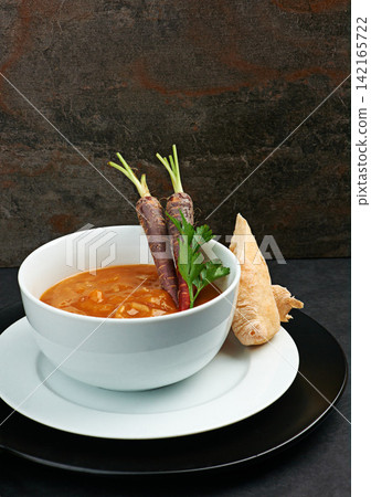 Vegetable, soup and bread on menu in restaurant with plate of healthy food for diet and nutrition benefits. Dinner, dish and luxury appetizer course in fine dining kitchen with carrot in bowl Vegetable, soup and bread on menu in restaurant with plate of healthy food for diet and nutrition benefits. Dinner, dish and luxury appetizer course in fine dining kitchen with carrot in bowl 142165722