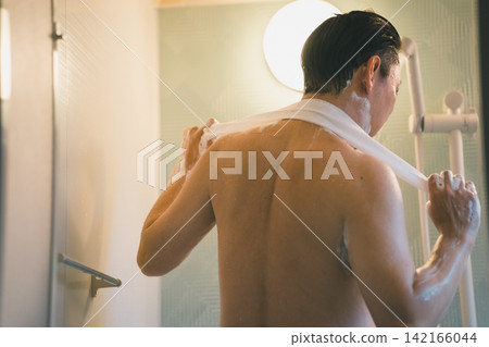 A man's bath time, washing his back with a body towel. A man's bath time, washing his back with a body towel. 142166044