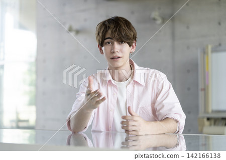 A young foreign man speaking while looking directly at the camera. A young foreign man speaking while looking directly at the camera. 142166138