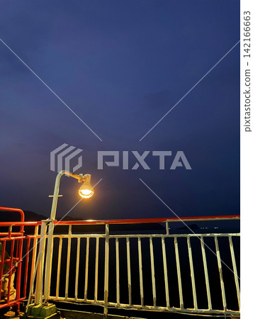 The illuminated ferry deck railing against the backdrop of a deep sunset sky The illuminated ferry deck railing against the backdrop of a deep sunset sky 142166663