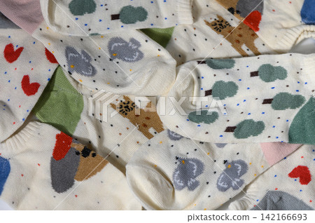 Pile of cute patterned socks with animals, trees, and hearts background Pile of cute patterned socks with animals, trees, and hearts background 142166693