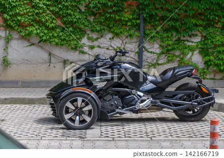 August 8, 2026, Tbilisi, Georgia Vibrant black motorcycle parked beside a wall covered in lush green ivy on a sunny day August 8, 2026, Tbilisi, Georgia Vibrant black motorcycle parked beside a wall covered in lush green ivy on a sunny day 142166719