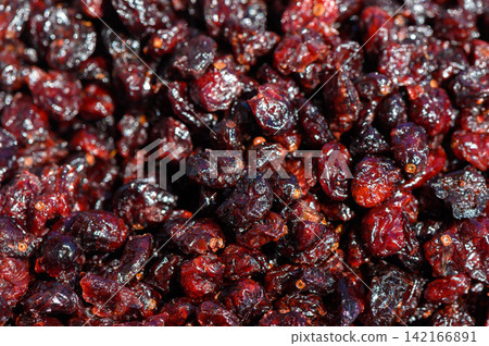 Vibrant and glossy dried cranberries glisten under the sun, showcasing their rich color in a market setting during the harvest season Vibrant and glossy dried cranberries glisten under the sun, showcasing their rich color in a market setting during the harvest season 142166891