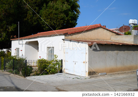 Quaint white house with red roof beside a quiet street in a sunny neighborhood Quaint white house with red roof beside a quiet street in a sunny neighborhood 142166932