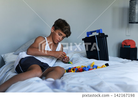 Happy, young boy and toys, playing on bed at home for learning, development and motor skills. Relax, male child and building blocks for growth and education for creative thinking and problem solving Happy, young boy and toys, playing on bed at home for learning, development and motor skills. Relax, male child and building blocks for growth and education for creative thinking and problem solving 142167198