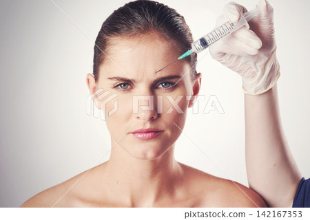 Woman, portrait and hand with injection in forehead or wrinkles plastic surgery, cosmetics or face lift. Female person, needle and frown lines for anti aging in studio, white background or filler Woman, portrait and hand with injection in forehead or wrinkles plastic surgery, cosmetics or face lift. Female person, needle and frown lines for anti aging in studio, white background or filler 142167353