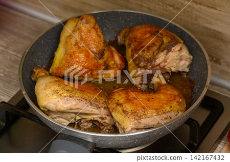Sizzling chicken legs cook to perfection in a skillet on a cozy kitchen stove Sizzling chicken legs cook to perfection in a skillet on a cozy kitchen stove 142167432