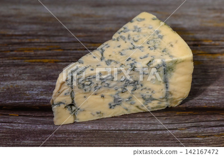 Delicious wedge of blue cheese resting on rustic wooden surface 142167472