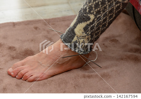 Close-up of a hand-knitted stocking in progress on a human foot Close-up of a hand-knitted stocking in progress on a human foot 142167594