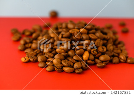 Freshly roasted coffee beans create a rich and vibrant scene on a bright red background Freshly roasted coffee beans create a rich and vibrant scene on a bright red background 142167821