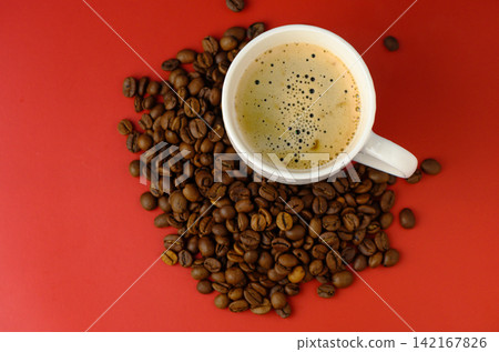 Freshly brewed coffee surrounded by rich roasted beans on a vibrant red background invites warmth and energy Freshly brewed coffee surrounded by rich roasted beans on a vibrant red background invites warmth and energy 142167826