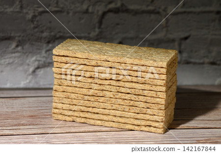 Stack of rectangular crispbread on a wooden surface against a dark brick wall Stack of rectangular crispbread on a wooden surface against a dark brick wall 142167844