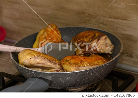 Sizzling chicken pieces cooked to perfection in a frying pan on a cozy kitchen stove Sizzling chicken pieces cooked to perfection in a frying pan on a cozy kitchen stove 142167860