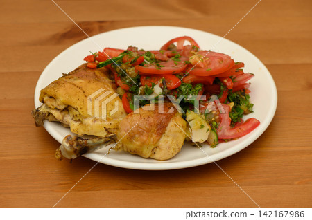 Roasted Chicken Pieces with Tomato Salad on a Wooden Table Roasted Chicken Pieces with Tomato Salad on a Wooden Table 142167986