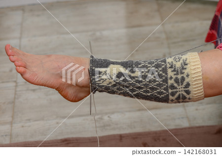 Side view of testing a long knitted stocking with a deer pattern on a foot Side view of testing a long knitted stocking with a deer pattern on a foot 142168031
