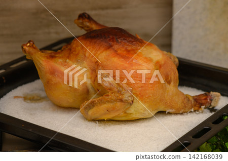 Golden roasted chicken sits on a silver tray ready for a delightful feast at a cozy kitchen Golden roasted chicken sits on a silver tray ready for a delightful feast at a cozy kitchen 142168039