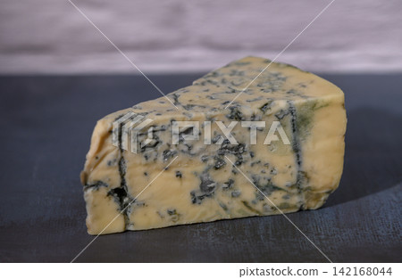 Cheese block showcasing rich textures and colors in a rustic kitchen setting, perfect for culinary delights Cheese block showcasing rich textures and colors in a rustic kitchen setting, perfect for culinary delights 142168044