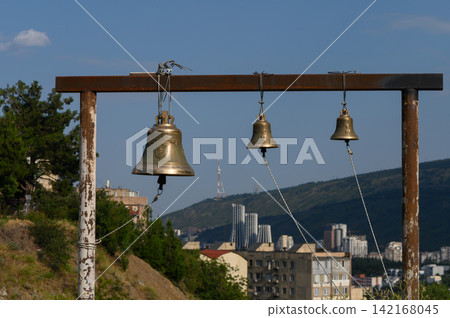 Bells ringing softly against the skyline of a bustling city on a bright day Bells ringing softly against the skyline of a bustling city on a bright day 142168045