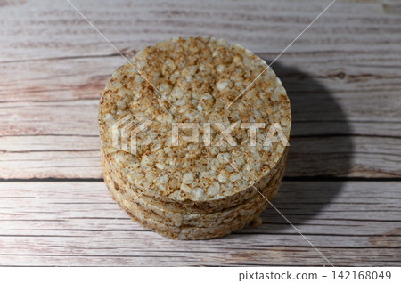 Top-down view of a round rice cake on a light wooden background Top-down view of a round rice cake on a light wooden background 142168049