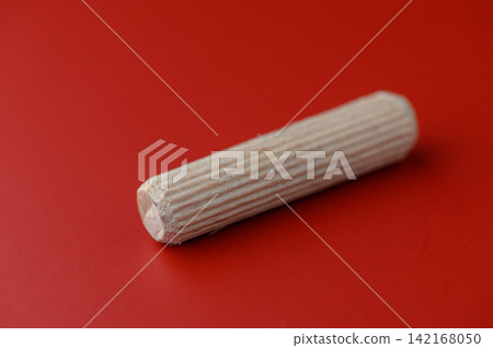 Wooden dowel resting on a bright red surface sparks creativity and imagination in crafting and woodworking projects during a sunny afternoon Wooden dowel resting on a bright red surface sparks creativity and imagination in crafting and woodworking projects during a sunny afternoon 142168050