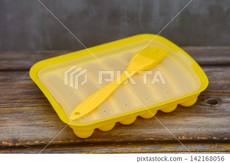 Covered Yellow Silicone Sausage Mold with Brush on Wooden Table Covered Yellow Silicone Sausage Mold with Brush on Wooden Table 142168056