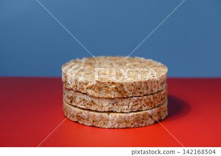 Stack of round rice cakes on a bright red surface with a blue background Stack of round rice cakes on a bright red surface with a blue background 142168504