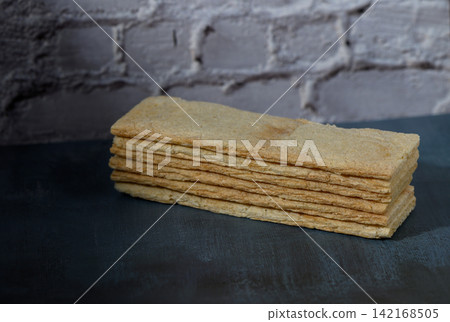 Stack of light-colored crispbread slices on a dark surface Stack of light-colored crispbread slices on a dark surface 142168505