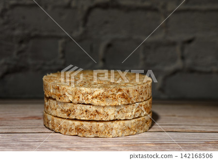 Stack of round rice cakes on a wooden surface against a dark brick wall Stack of round rice cakes on a wooden surface against a dark brick wall 142168506